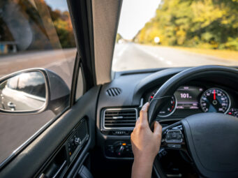 Woman driver's hands on the steering wheel inside the car.